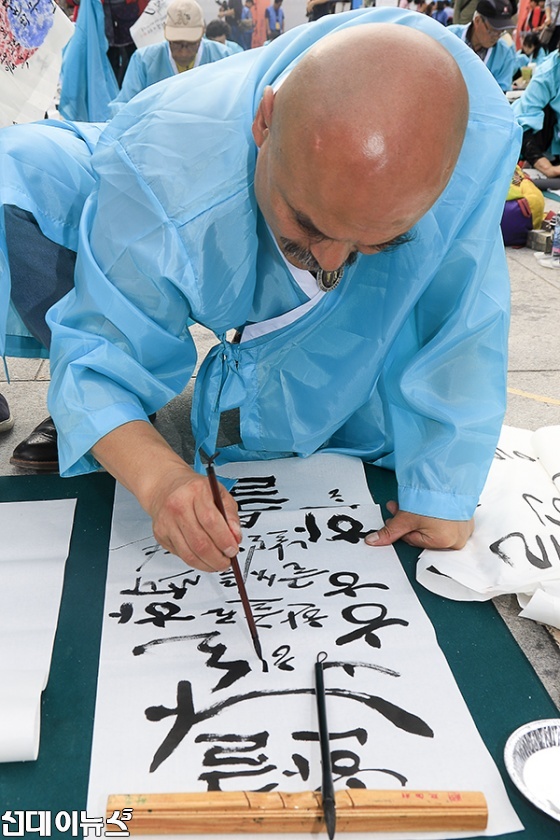 571돌 한글날을 맞아 9일 오전 서울 광화문광장에서 열린 한글휘호경진대회에서 한 참가자가 휘호를 쓰고 있다.