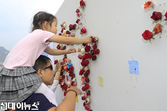 571돌 한글날을 맞아 9일 오전 서울 광화문광장에서 꽃을 꽂아 글자쓰기 판에 한 어린이가 아빠 목 등을 탄 채 꽃을 꼽고 있다.